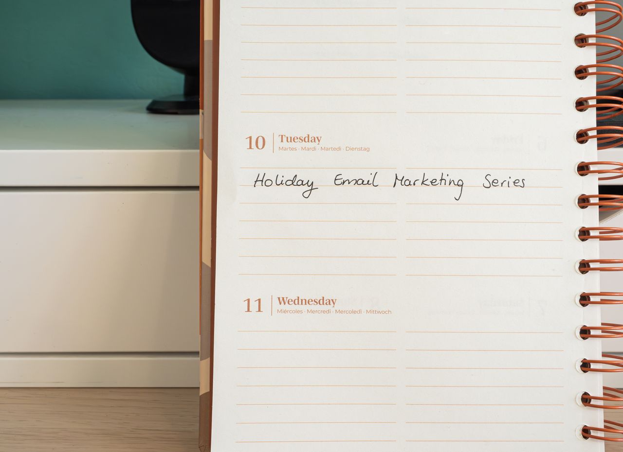 Plánovač otevřený na stole s ručně psanou poznámkou Holiday Email Marketing Series.